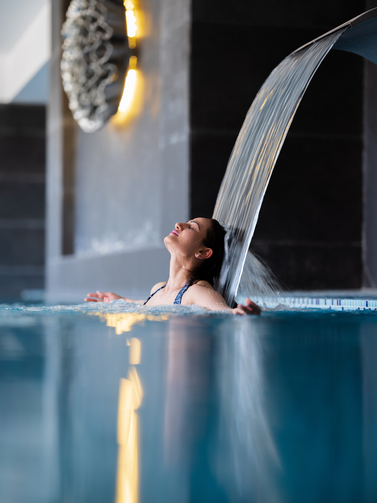 GFXS1253 A spacious and well-appointed hotel room featuring a king-sized bed, light yellow seating, and coastal-inspired artwork with a sophisticated color palette and wooden floors.