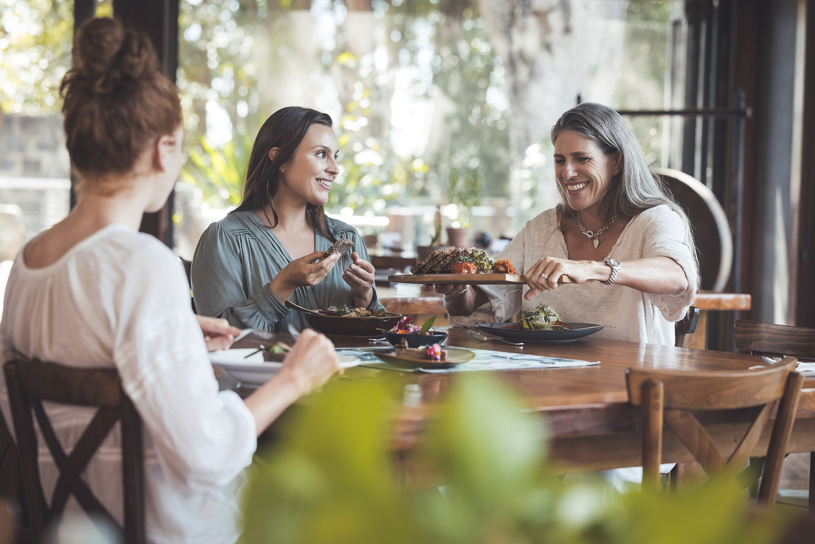 Gwinganna-123 A woman in a white bathrobe sits on a cushioned bench near elegant sculptural lighting, creating a calm and luxurious wellness environment.