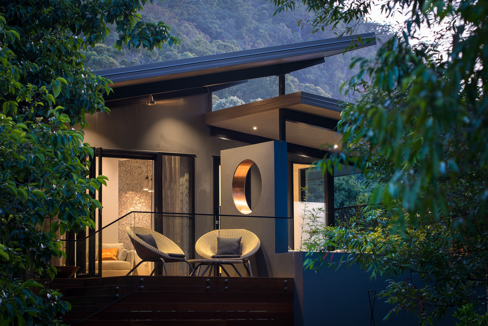 Gwinganna Lifestyle Retreat – Meditation Suites A person rests peacefully in a green hammock surrounded by lush forest trees, wearing headphones and looking serene.