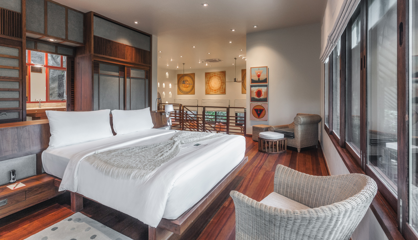 An infinity pool overlooking a serene tropical coastline, surrounded by lush trees and greenery with a stunning ocean and distant islands in the background. The pool area features comfortable loungers and an elegant open-air design.